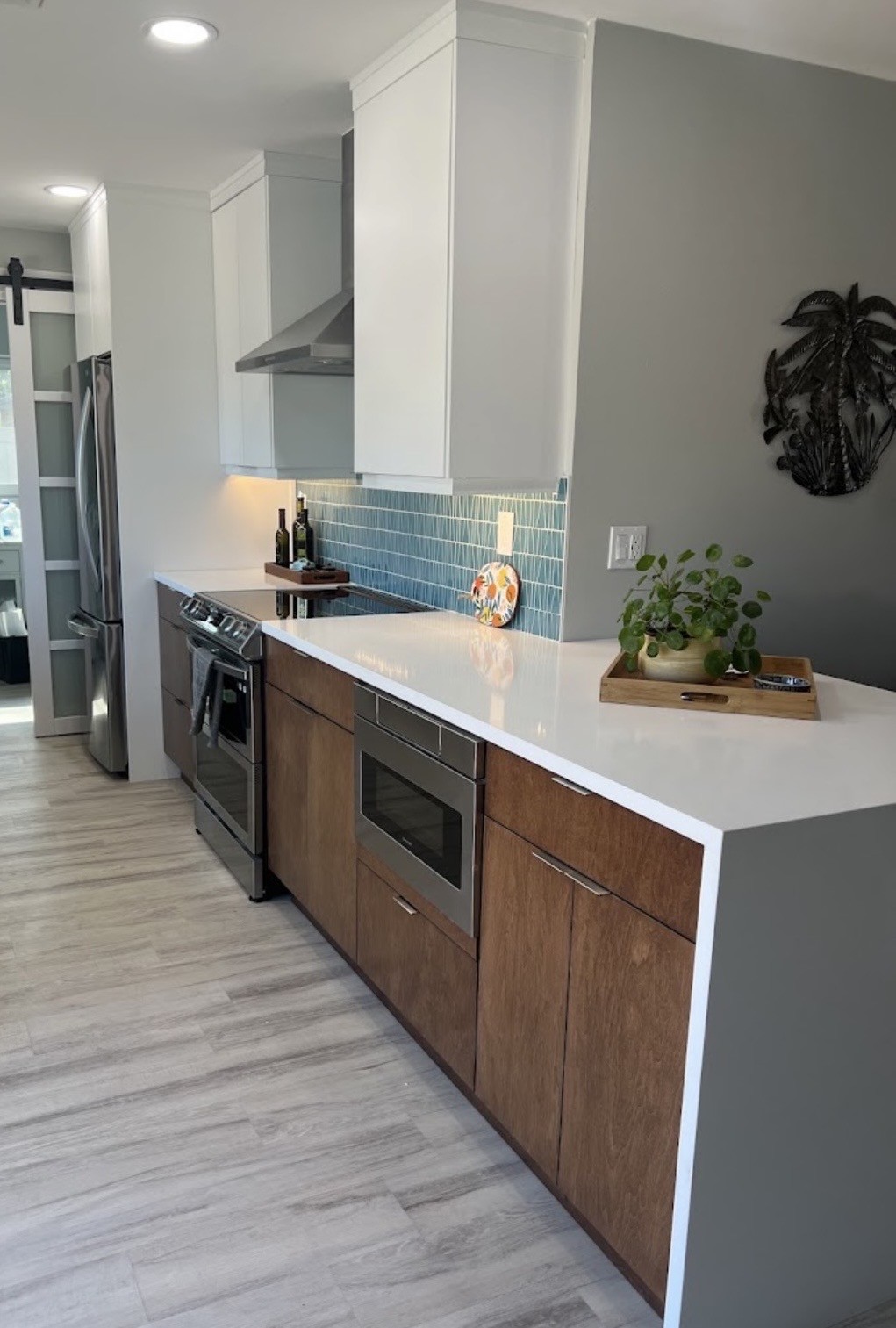 Bright coastal kitchen remodel with white upper cabinets, warm wood lower cabinets and turquoise backsplash tile