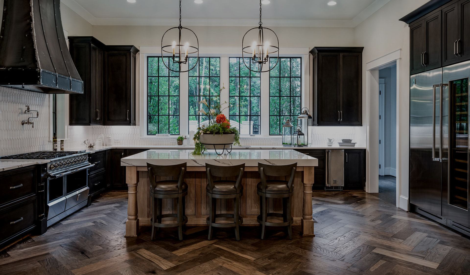 Dark wood kitchen remodel with a large marble island and herringbone wood floor