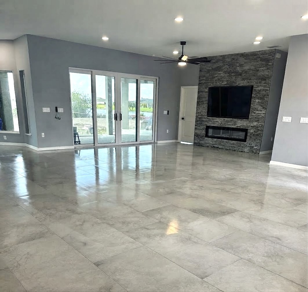 Spacious renovated living room with polished tile flooring, stacked stone fireplace wall and sliding glass doors